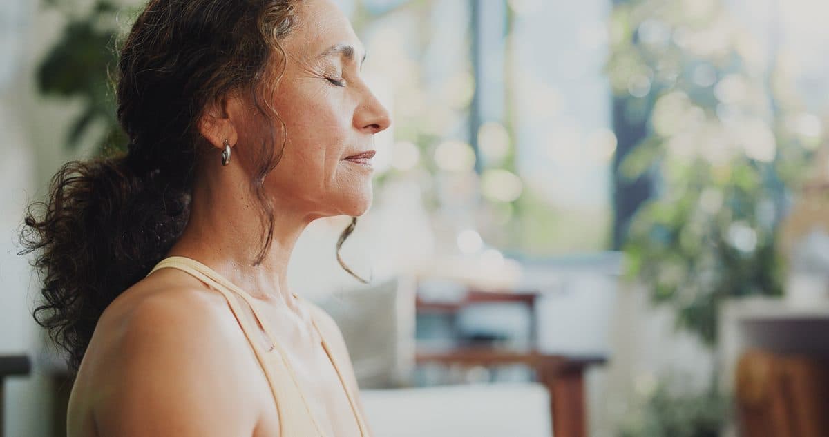 A woman relaxing calmly at home with her eyes closed